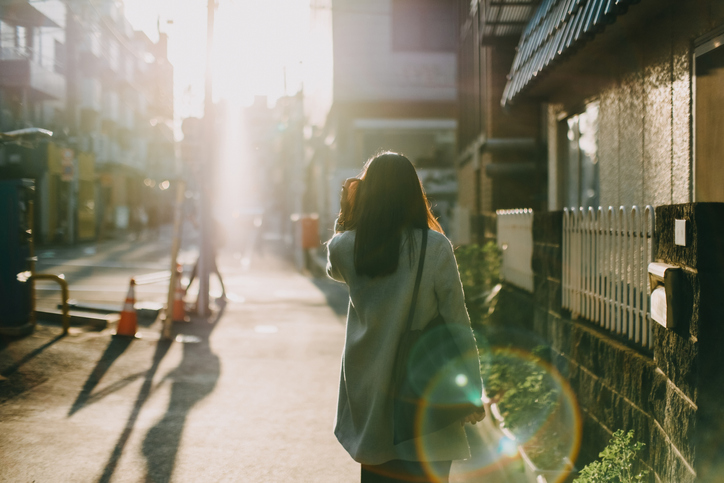 Rear view of woman leaving her traveling nurse housing to work in the early morning against warm sunlight